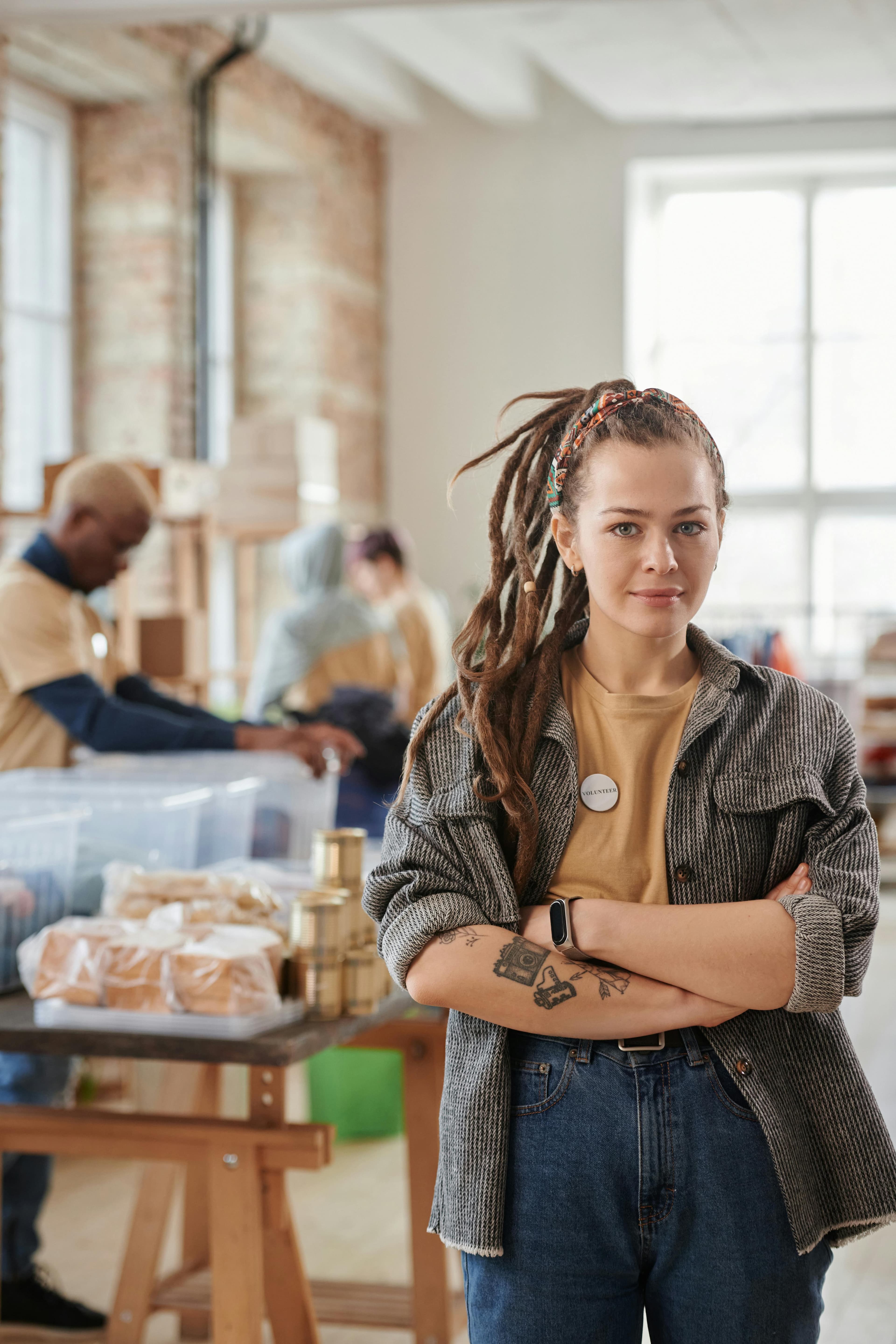 Volunteer with arms crossed standing in a community workspace.